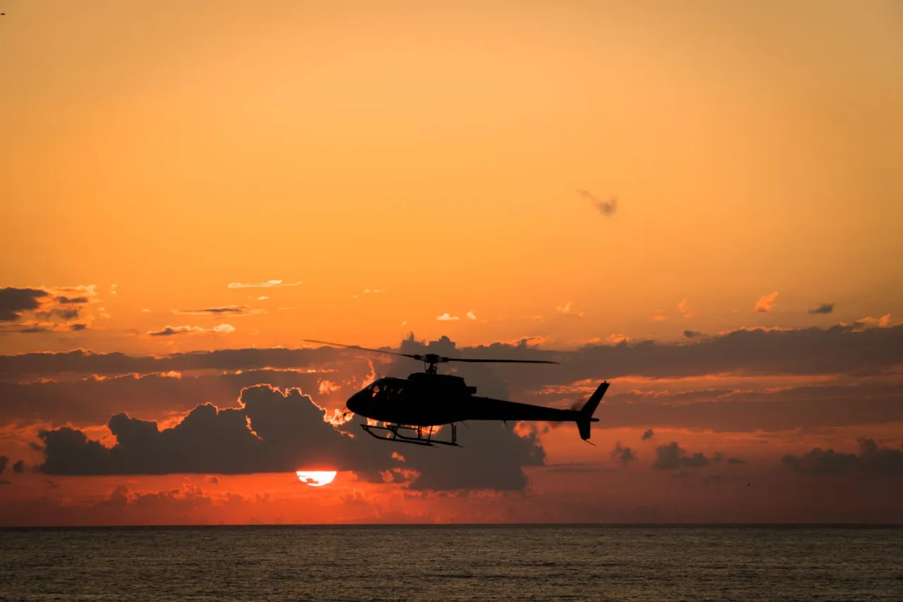 A helicopter silhouetted against a dramatic sunset